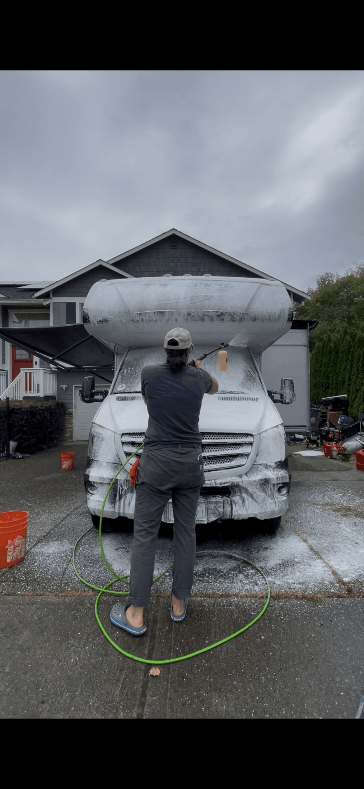 Hula Girl RV Care technician washing a soapy motorhome in a driveway