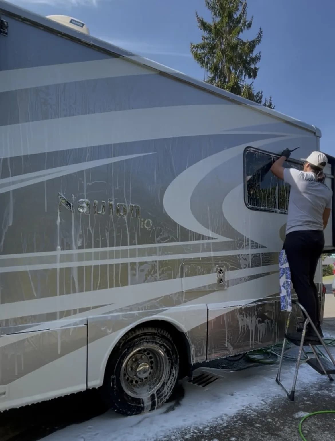 Hula Girl RV Care technician hand washing the soapy exterior of a motorhome
