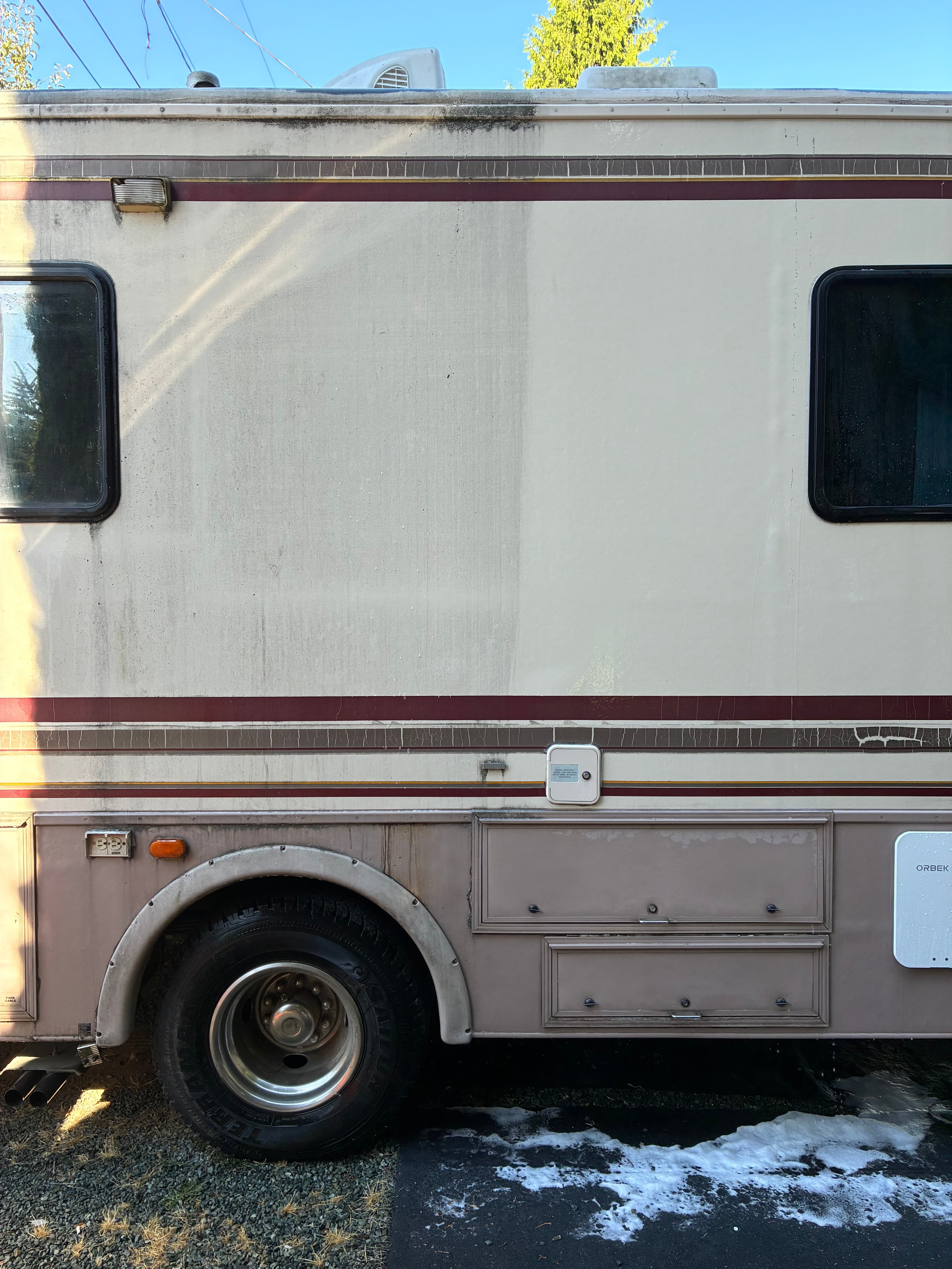 Motorhome side panel split view — left half dirty with oxidation, right half freshly washed and restored by Hula Girl RV Care in Monroe, WA